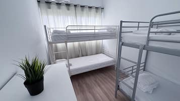 Dormitorio con literas, una mesita pequeña y una planta en maceta.