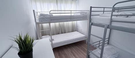 Une chambre avec un lit superposé, une petite table et une plante en pot.