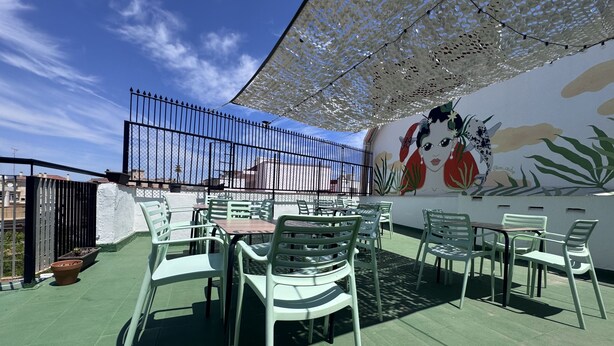 Un patio al aire libre con mesas y sillas, un mural decorativo y una cerca.