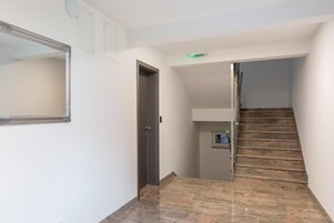 A hallway with a wooden staircase, a door, and a small window.