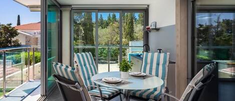 A balcony with a glass door, a round table with chairs, and a small potted plant.