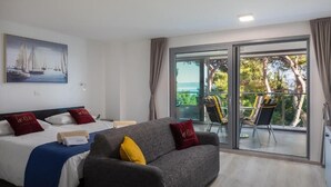 Una camera d'hotel con un letto, un divano e un balcone vista mare.