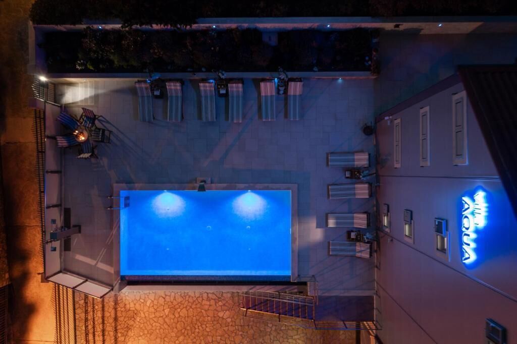 Ein Poolbereich auf dem Dach mit großem Pool, Sitzgelegenheiten im Freien und einem Neon-Schild.
