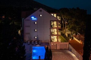 A modern hotel with a swimming pool, a sign reading "AQUA", and a glass-enclosed upper level. - VILLA AQUA - Adults Only (Bol)