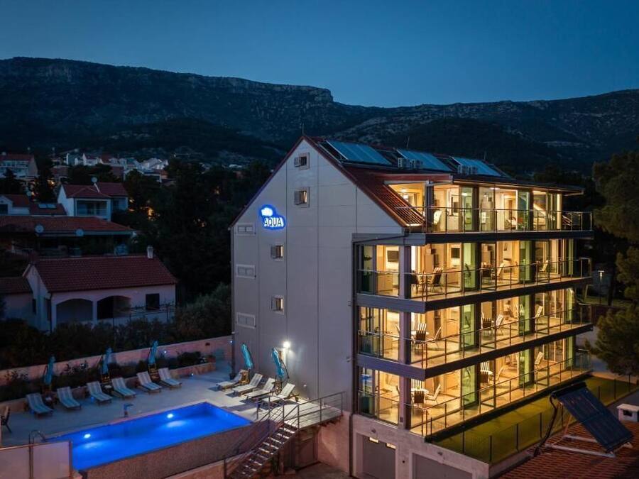 A modern hotel with a pool, multiple floors, and a view of the surrounding landscape.