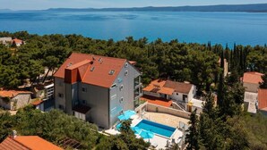 Un edificio con piscina, circondato da alberi e affaccio su un ampio specchio d'acqua.