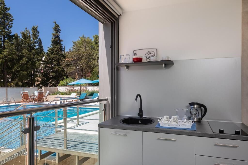 A modern kitchen with a sink, a coffee maker, and a shelf with kitchenware.