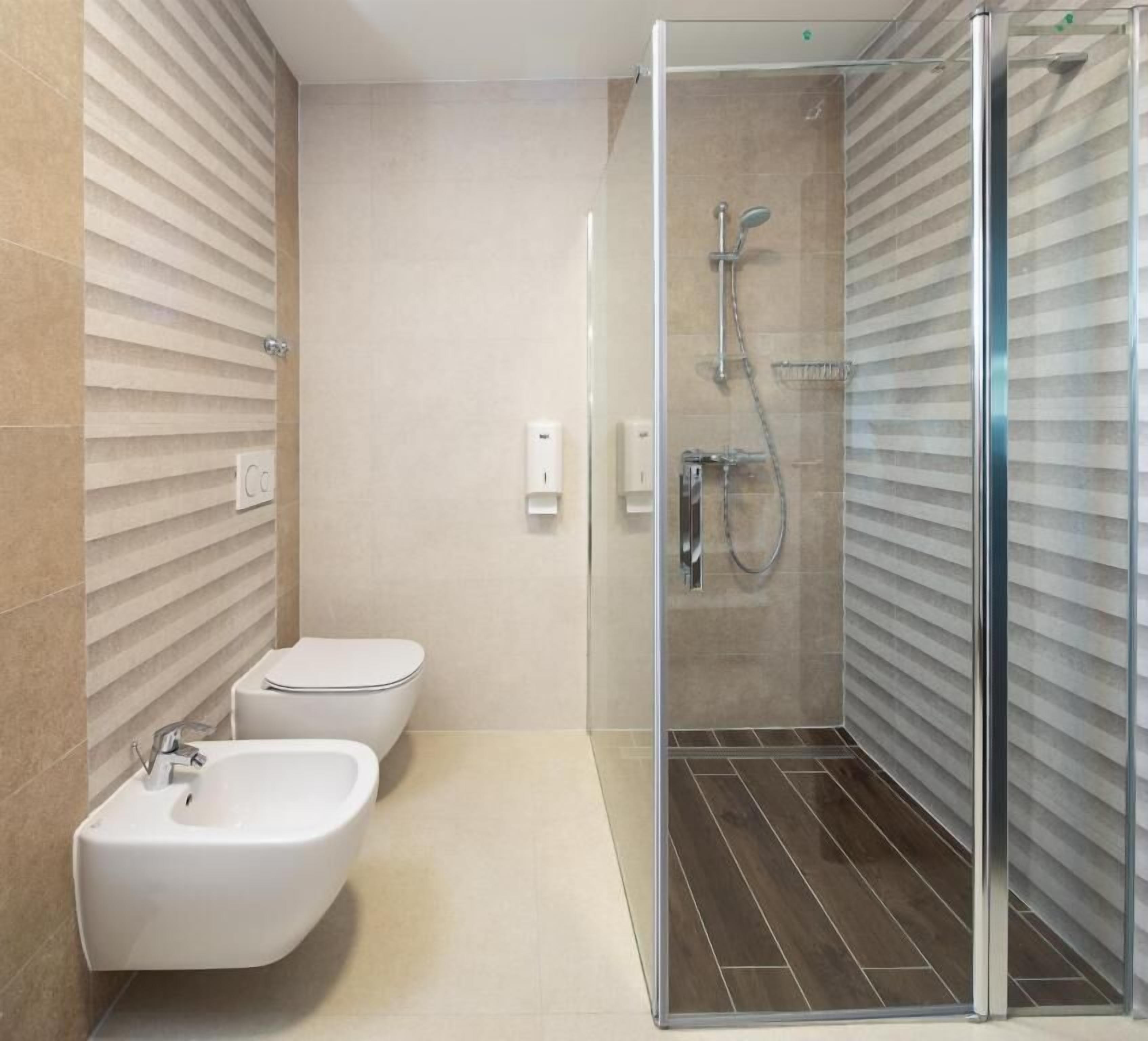 A modern bathroom with a glass-enclosed shower, two sinks, and a toilet.