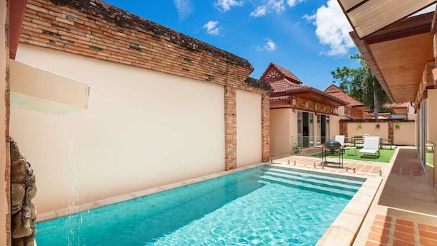 A swimming pool with clear blue water, surrounded by a brick wall and a covered patio area with outdoor seating. - Balinese 3BR Pool Villa Freya in Rawai (Rawai)