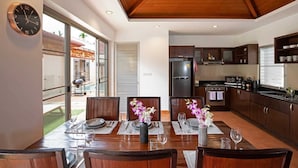 A modern kitchen with dark wooden cabinets, a built-in oven, and a refrigerator. - Balinese 3BR Pool Villa Freya in Rawai (Rawai)