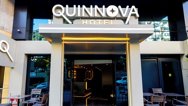 The entrance to the Quinnova Hotel with a modern design, featuring a prominent sign and outdoor seating area. - Quinnova Hotel (Istanbul)