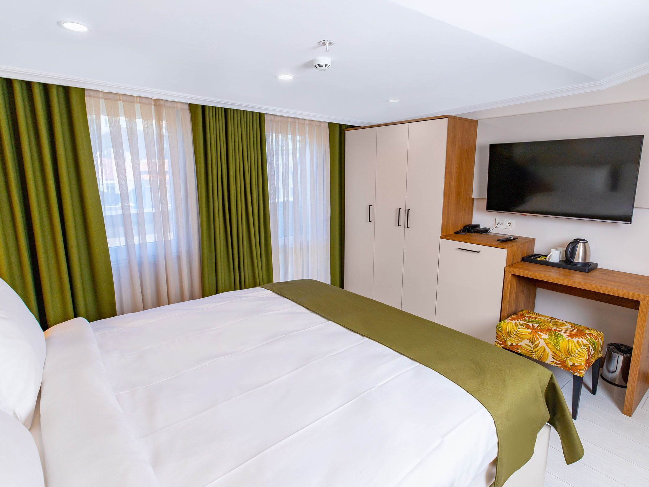 Een hotelkamer met een bed, een bureau met een televisie en een klein tafeltje met een waterkoker.