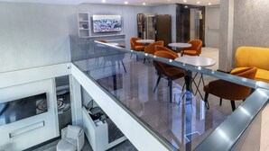 A modern dining area with glass railings, orange chairs, and a yellow sofa. - Quinnova Hotel (Istanbul)