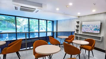 Una sala de conferencias moderna con ventanas amplias, sillas anaranjadas y una pizarra.