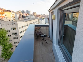 A balcony with a table and chairs, overlooking a cityscape.