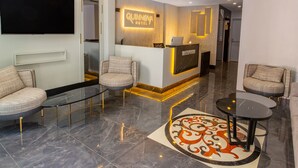 A hotel reception area with a modern design, including a reception desk, seating area, and a decorative rug. - Quinnova Hotel (Istanbul)