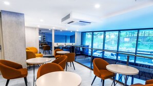 A modern interior with round tables and orange chairs, large windows offering a view of the outside. - Quinnova Hotel (Istanbul)