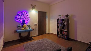 Un salon avec un plancher en bois, une bibliothèque, une statue et un luminaire fixé au mur.