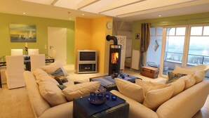 A cozy living room with a fireplace, comfortable seating, and a view of the outdoors. - Hof Eckhorst - View apartment - Stylish ambience & cozy atmosphere (Güby)