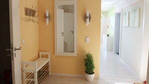 A hallway with a bench, a potted plant, and a mirror on the wall. - Hof Eckhorst - View apartment - Stylish ambience & cozy atmosphere (Güby)