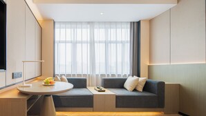 A modern hotel room with a sofa, a small round table, and a view of the city through large windows. - Rezen Longuu Hotel - Guangzhou Baiyun Airport Cultural Tourism City (Guangzhou)