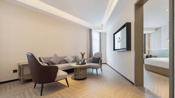 Een moderne hotelkamer met een bank, fauteuils, een klein rond tafeltje en een bed.