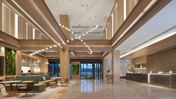 A spacious lobby with a reception desk, seating area, and a large window offering a view. - Rezen Longuu Hotel - Guangzhou Baiyun Airport Cultural Tourism City (Guangzhou)