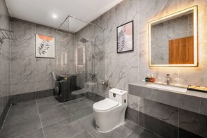 A modern bathroom with a glass-enclosed shower, a toilet, and a sink with a mirror above it.