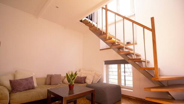 A living room with a wooden staircase, a sofa, a coffee table, and a window.