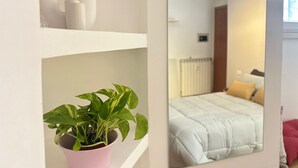 A bedroom with a bed, a radiator, and a mirror reflecting the room.