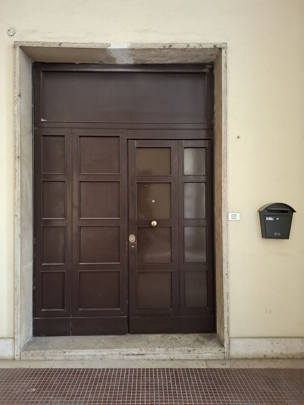 A large, dark brown double door with a metal handle and a mail slot on the right side.