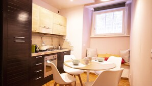 A modern kitchen with dark cabinetry, a wooden countertop, and a dining area with white chairs and a round table.