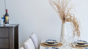 A dining table set with plates, a vase with dried branches, and a bottle of wine. - 3-Bedroom Apartment in Prizba with Ocean Views - Ideal for Families and groups (Smokvica)