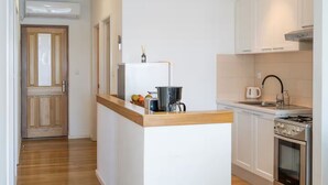 A modern kitchen with white cabinets, a wooden countertop, a built-in oven, and a coffee maker. - 3-Bedroom Apartment in Prizba with Ocean Views - Ideal for Families and groups (Smokvica)