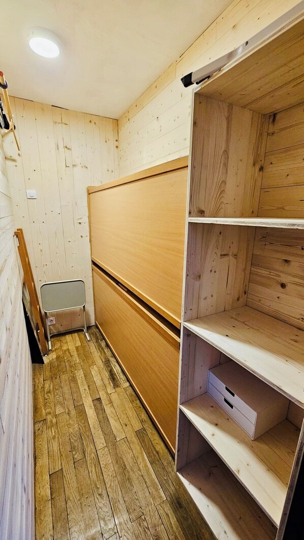 A room with wooden walls and a wooden floor, featuring a built-in bench and a shelving unit. - Apartment with two small bedrooms and a separate kitchen near the spa (Brides-les-Bains)