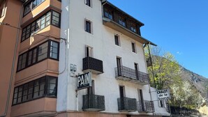 Un immeuble à plusieurs étages, doté de balcons et d’enseignes indiquant « PAIN » et « CHALET de la Source ».