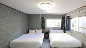 Ein Zimmer mit zwei Betten, einem Fenster mit Vorhängen, einem kleinen Tisch und einer Deckenleuchte.