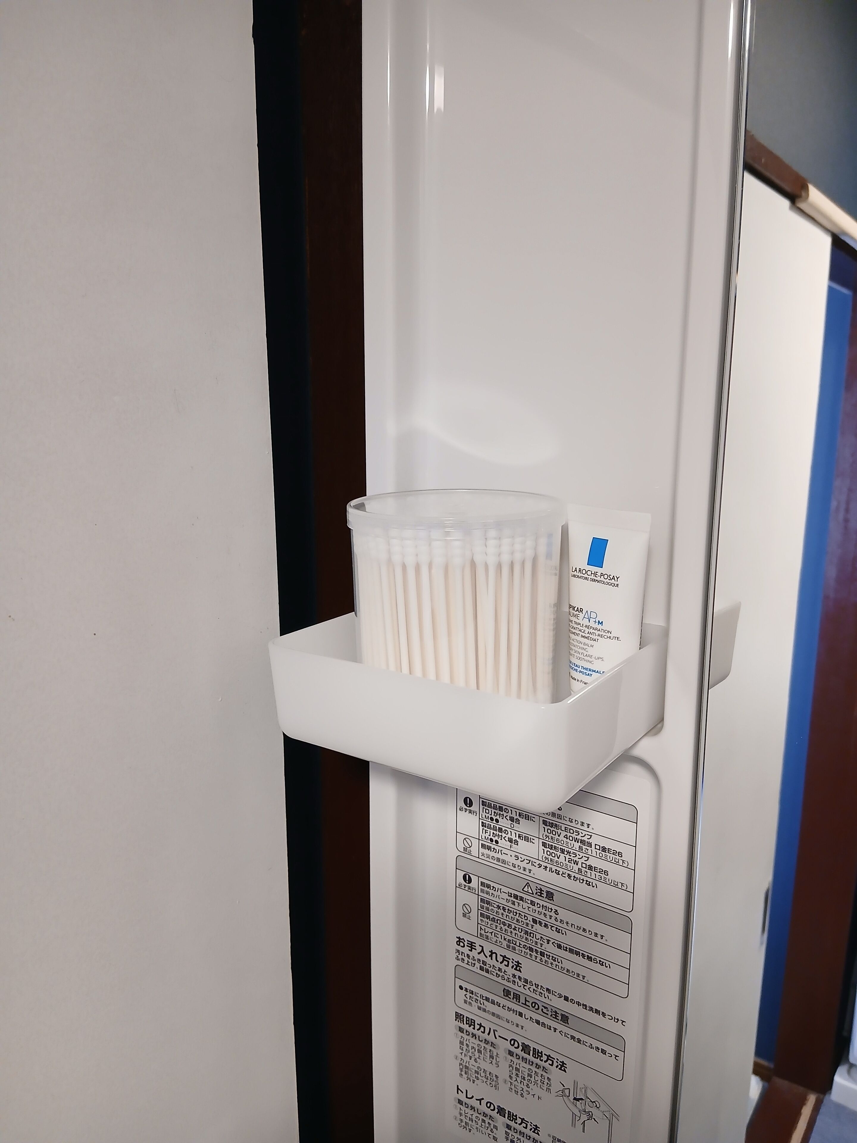 A white shelf with a container of cotton swabs and a box of tissues.