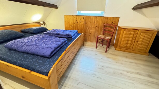 A bedroom with a wooden bed, a chair, and a wooden cabinet. - Bungalow near Grevelingenmeer (Brouwershaven)