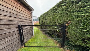 Een omheind gebied met een houten omheining en een haag.
