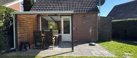 A house with a covered patio, a brick exterior, and a satellite dish.