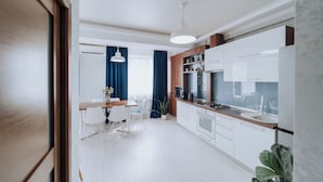 A modern kitchen with white cabinets, a wooden countertop, and a dining area with a table and chairs.