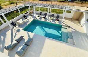 An outdoor swimming pool with lounge chairs and a covered seating area.