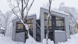 A modern building with large windows and a snow-covered exterior. - Origami Twins (Hakuba)
