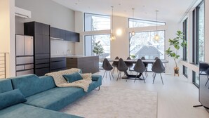 A modern kitchen with dark cabinets, a built-in refrigerator, and a dining area with a table and chairs. - Origami Twins (Hakuba)