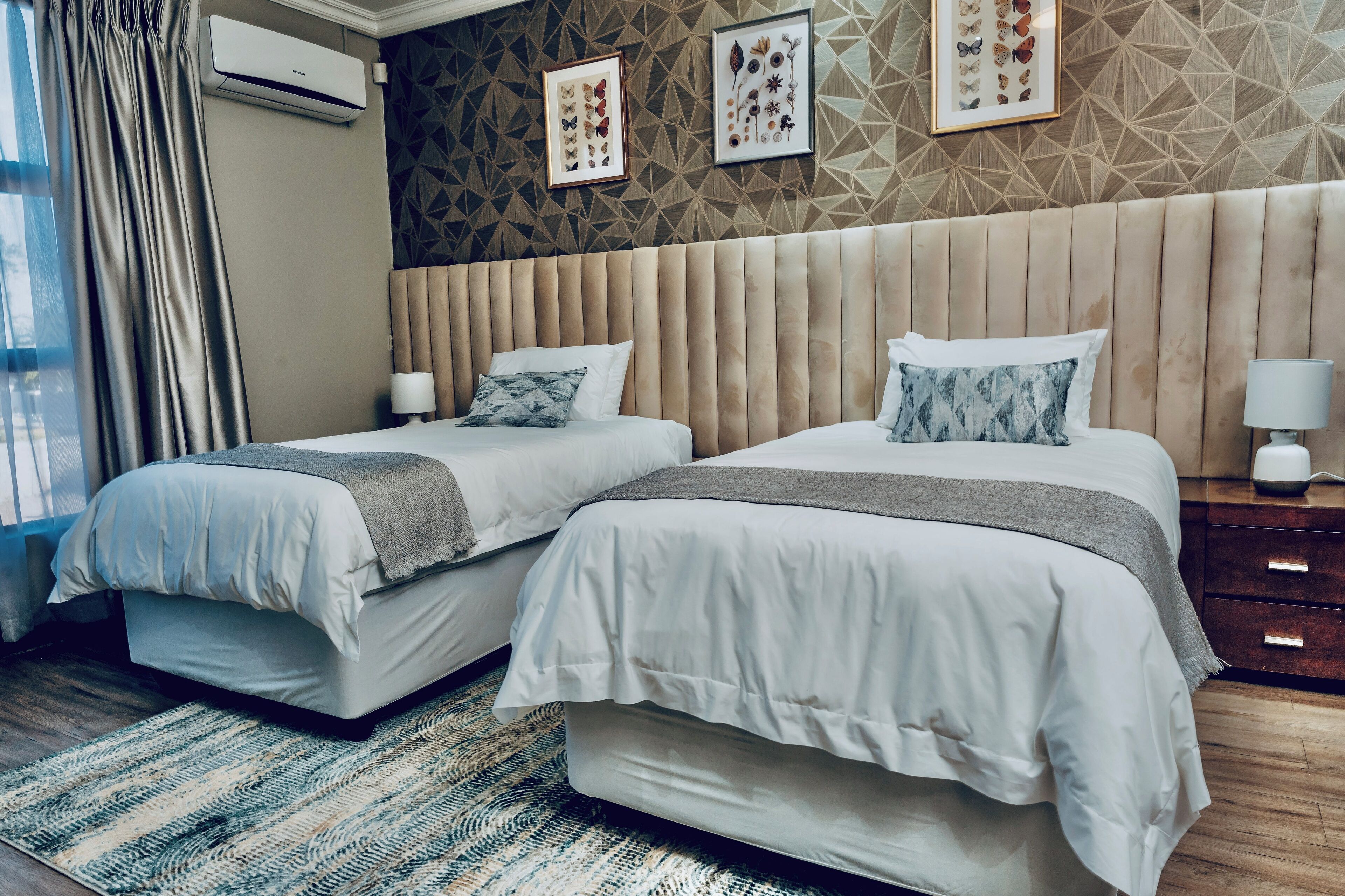 A hotel room with two beds, a patterned wall, and a geometric design.