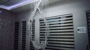 Un intérieur moderne agrémenté d’un lustre en cristal décoratif, d’un panneau indiquant l’emplacement de la réception, de la piscine, du restaurant et de la sortie de secours.