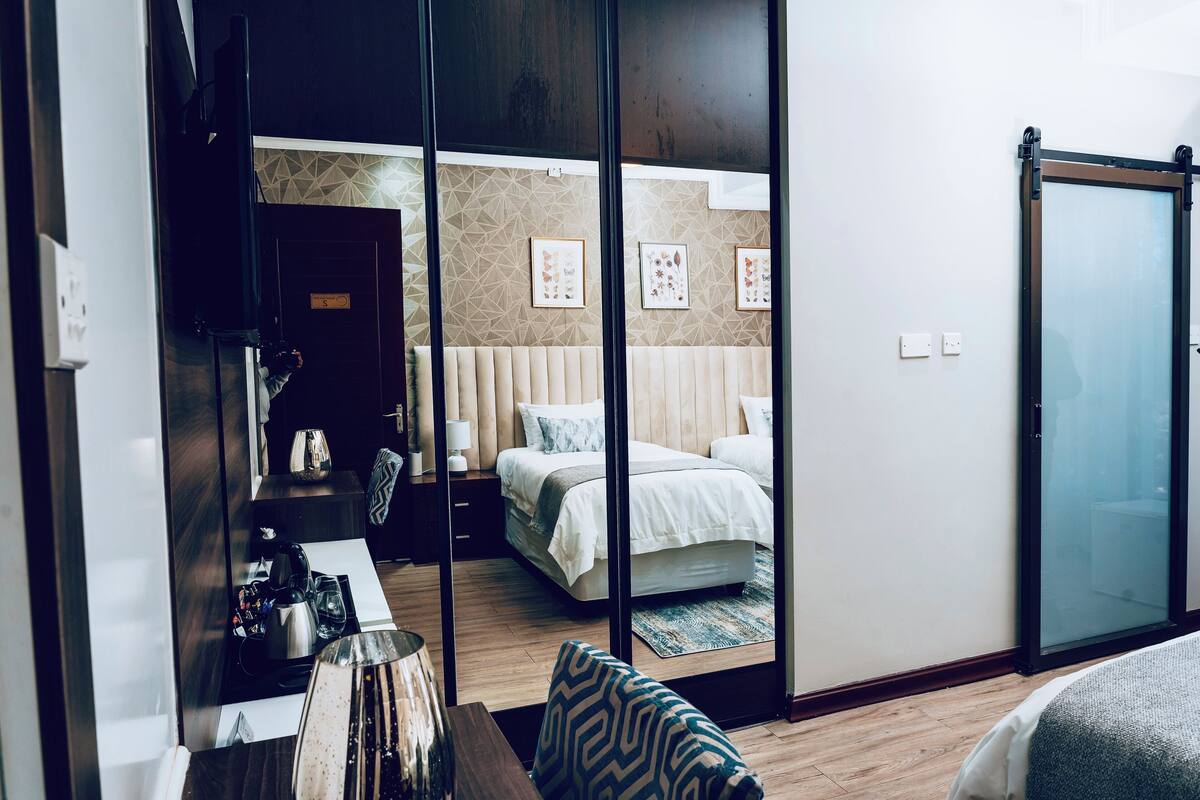 A hotel room with a bed, bedside table, lamp, and a mirror.