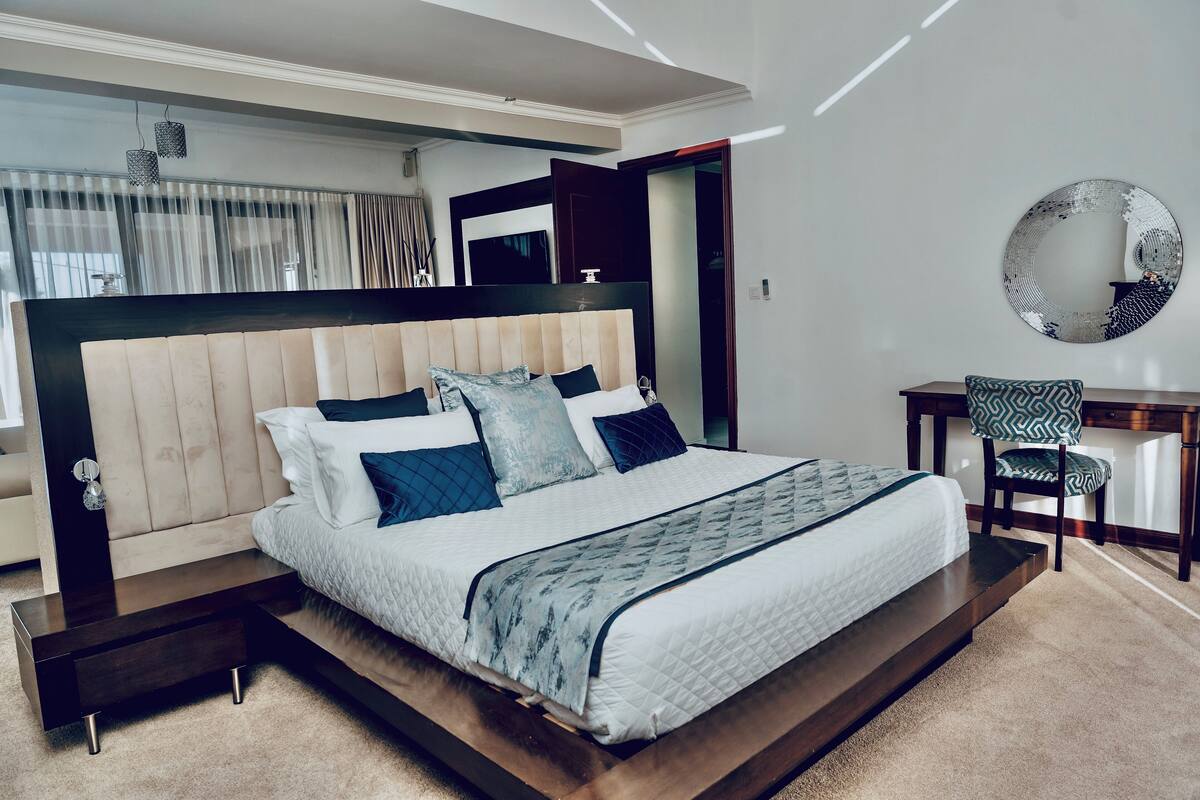 A modern bedroom with a large bed, bedside tables, a desk, and a chair.