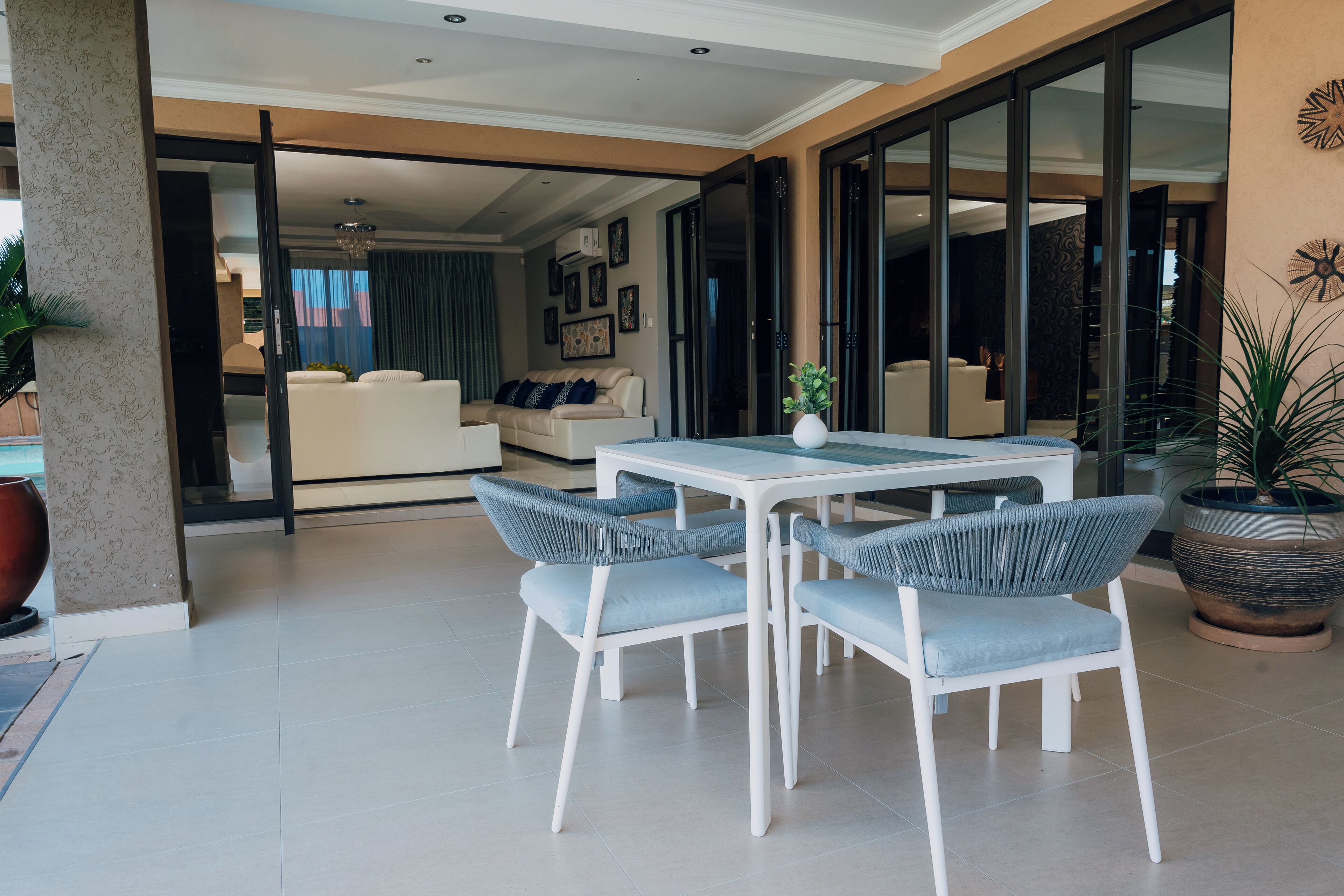 Een moderne zithoek met een eettafel en stoelen, een bank en een groot raam.
